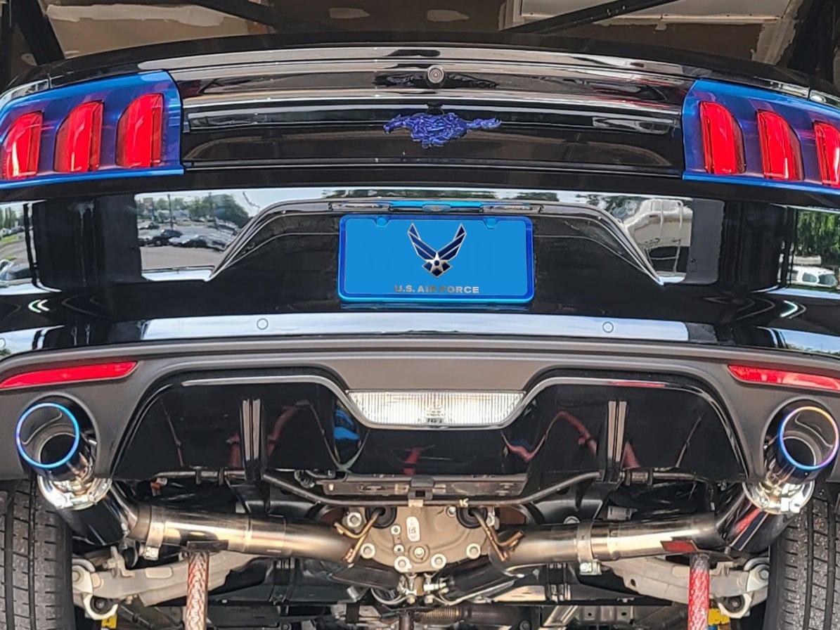 Rear underside view of a late-model Ford Mustang with a dual-exit performance cat-back exhaust system, featuring polished titanium-style exhaust tips, mandrel-bent piping, and an independent rear suspension.