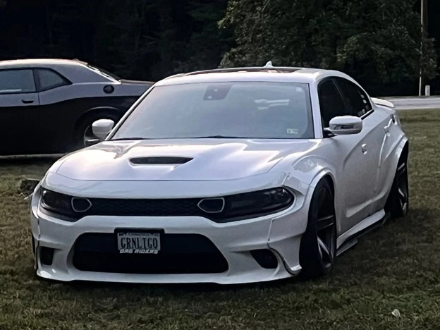 White Dodge Charger with an aggressive lowered stance and noticeable negative front camber, showcasing a performance-oriented suspension setup.