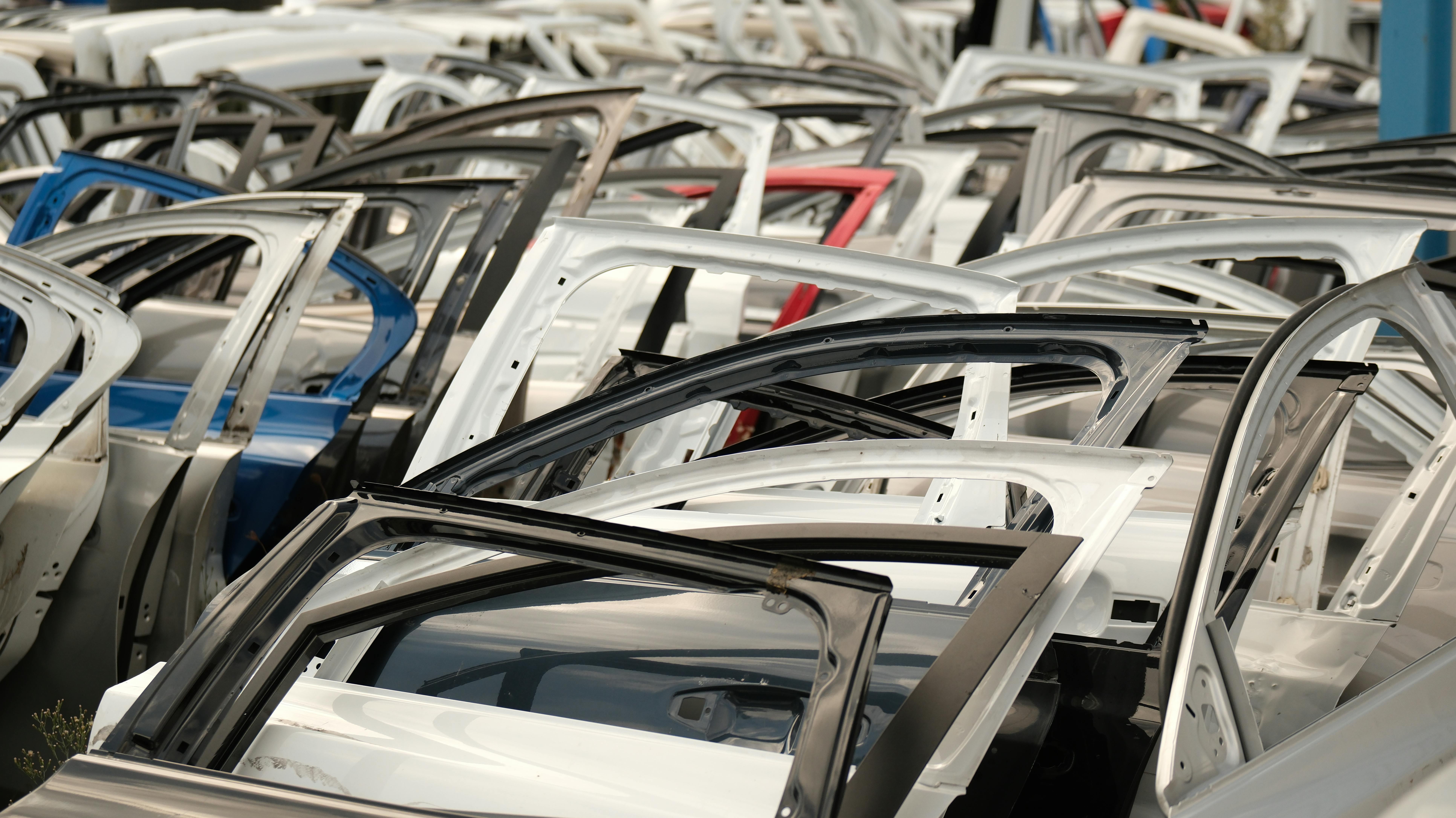 Large collection of salvaged vehicle door frames and body panels organized at an automotive recycling facility.